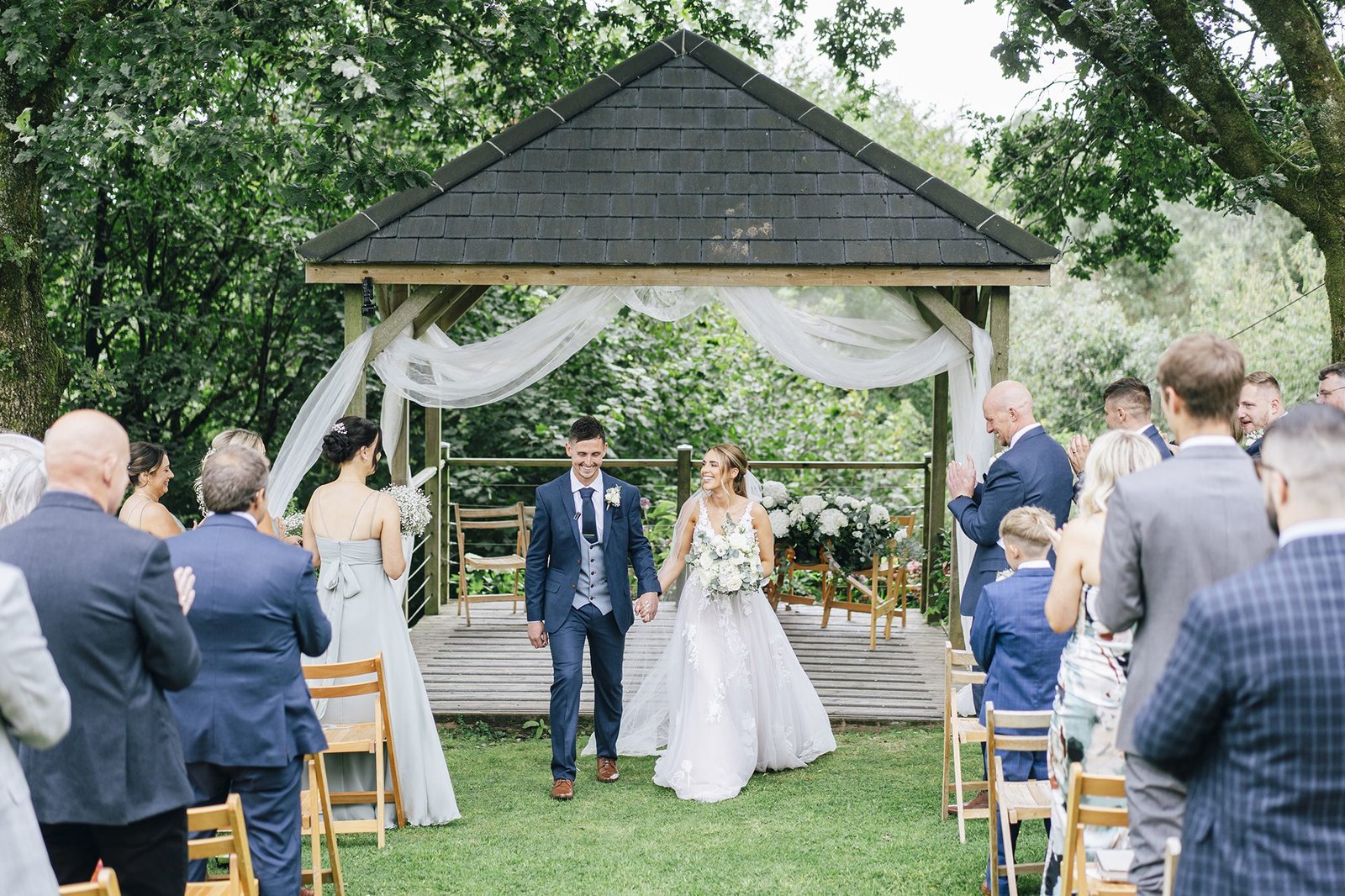 The green Cornwall bride and groom walking down a aisle